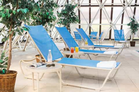 Indoor spa lounge with blue recliners, white lattice windows, and potted plants