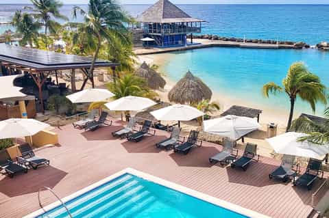 Tropical beach resort with lagoon pool, thatched cabanas, and clear water