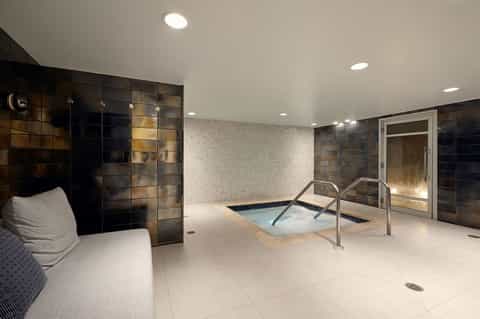 Spa area with hot tub, shower enclosure, and dark tile walls