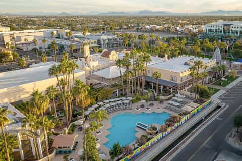 Aerial view of resort with blue pool, white tent structures, and palm trees