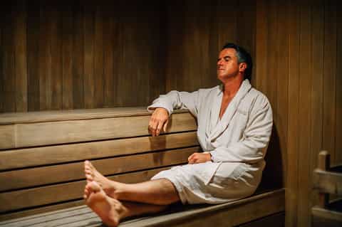 Man relaxing in wooden sauna with bench seating