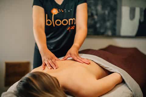 Massage therapist providing treatment wearing Bloom spa shirt