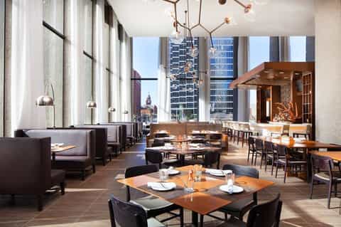 Upscale restaurant with floor-to-ceiling windows, pendant lighting, and city skyline views