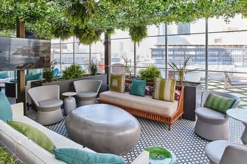 Rooftop lounge area with modern seating, hanging plants, and urban cityscape views