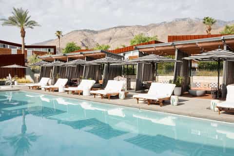 Modern pool resort with striped cabanas, lounge chairs, and mountain desert backdrop