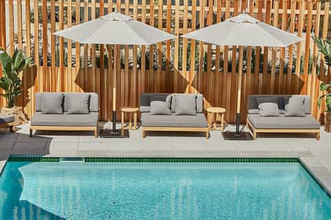 Poolside lounge area with wooden furniture, umbrellas, and modern pool deck