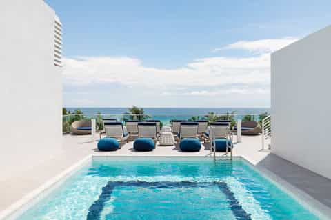 Private rooftop pool overlooking ocean with lounge chairs and sea view