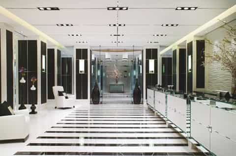 Modern spa corridor with white and black marble floors, glass partitions, and minimalist decor