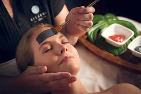 Spa facial treatment with aesthetician applying facial mask to client's face