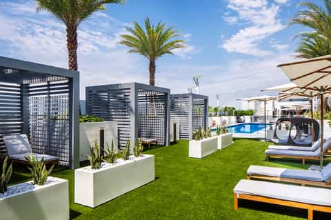 Modern poolside cabanas with privacy screens, lounge beds, and manicured grass