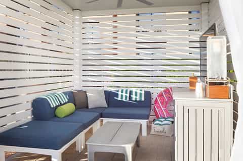 Coastal condo cabana with navy seating, striped privacy screens, and poolside table setting