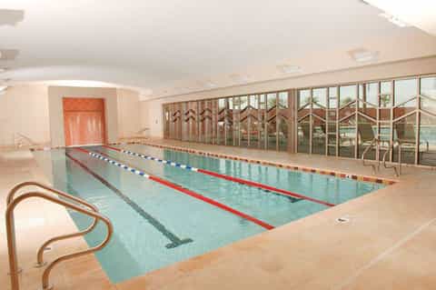 Indoor lap pool with lane dividers, large windows, and modern ceiling lighting