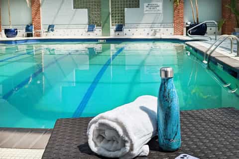 Swimming pool with lane markings, white towel and blue water bottle on dark poolside