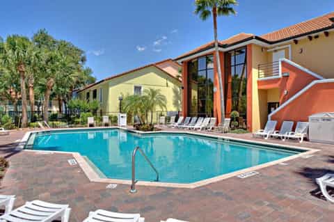 Resort pool surrounded by colorful buildings, palm trees, and white lounge chairs