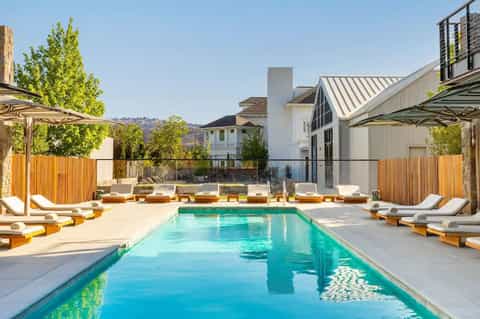 Rectangular lap pool surrounded by lounge chairs, umbrellas, and modern architecture