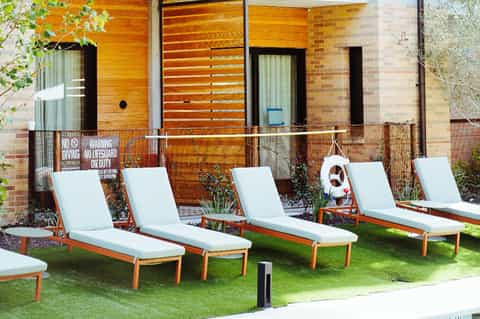 Modern residential building with lounge chairs on grass lawn and contemporary architectural design