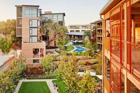Modern residential courtyard with red brick buildings, small pool, landscaping, and walking paths