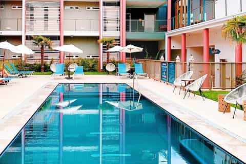 Vibrant retro-style hotel pool with colorful building facade and lounge chairs