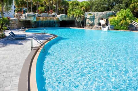 Resort pool with rock waterfall feature and tropical landscaping