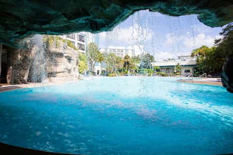 Turquoise indoor pool surrounded by cave-like stone walls and tropical plants