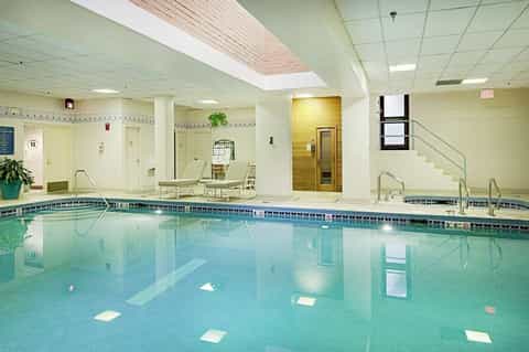 Indoor aquatic facility with lap pool, lounge chairs, and fitness amenities