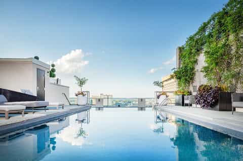Rooftop infinity pool with city skyline views and modern lounging area