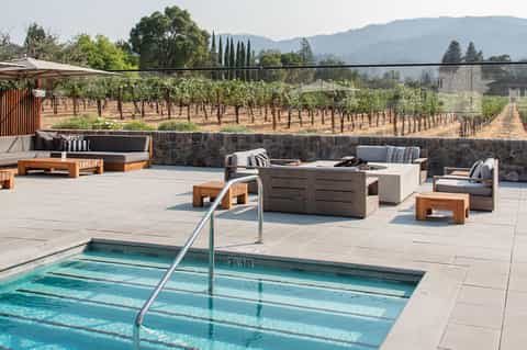 Resort pool overlooking vineyard landscape with lounge seating and fire pit