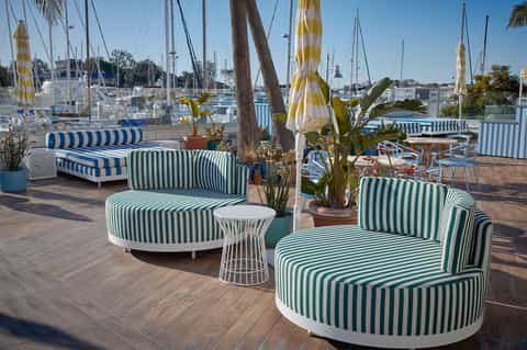Marina lounge seating with striped furniture, sailboats, and waterfront views