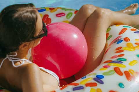 Child floating on colorful pool float in swimming pool