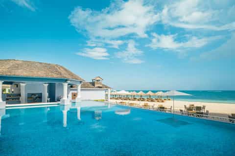 Luxury beachfront infinity pool overlooking white sand beach and turquoise ocean