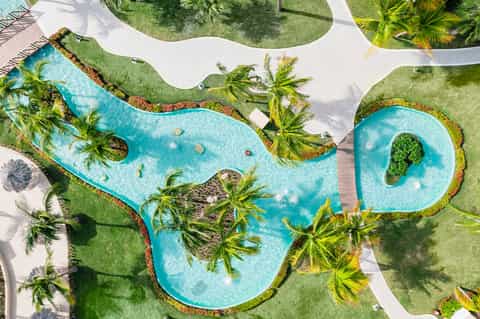 Aerial view of lagoon-shaped swimming pools surrounded by palm trees and manicured landscaping