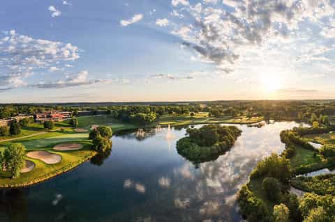 Aerial landscape view of golf course with water hazards, green fairways, and tree-lined course