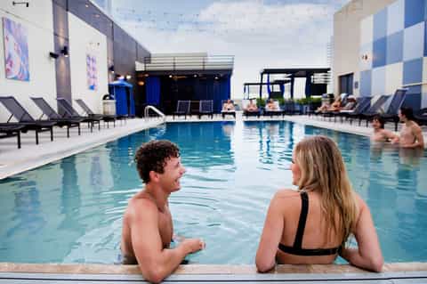 Modern indoor pool with blue water, contemporary furnishings, and architectural design