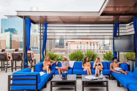Rooftop lounge with blue seating, city skyline views, and outdoor bar area
