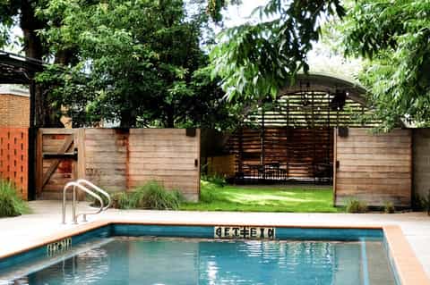 Residential pool with steel railings surrounded by wooden fence and mature trees