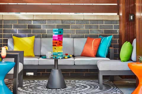 Modern lounge seating with colorful pillows, Jenga game, brick accent wall, and contemporary design