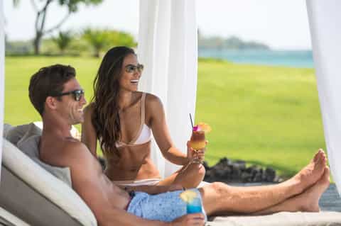 Couple enjoying tropical cocktails in lounge chairs overlooking ocean