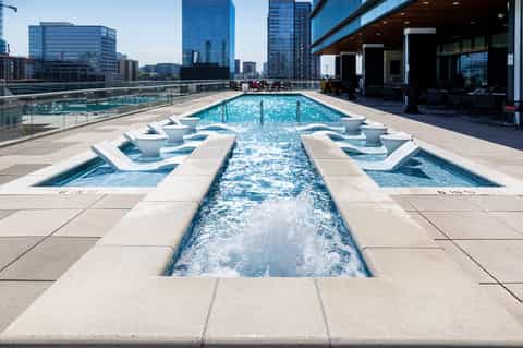 Rooftop pool deck with modern loungers overlooking urban skyline and city buildings