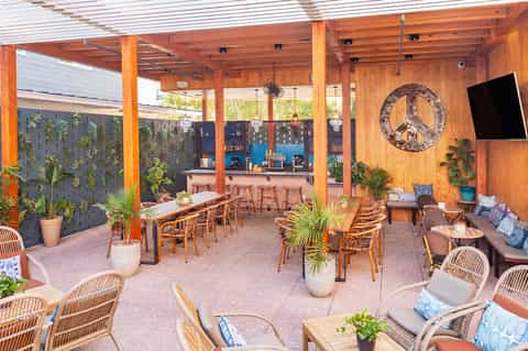Modern covered patio area with wooden structure, bar, and lounge seating with plants