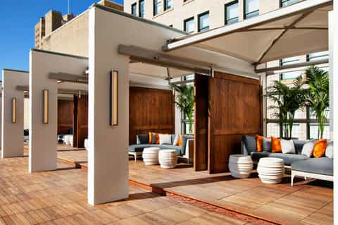 Modern rooftop terrace with white pergolas, gray seating, and potted plants