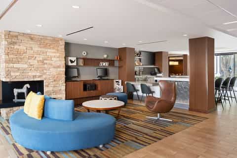Modern hotel lobby lounge with blue circular seating, fireplace, and contemporary furnishings