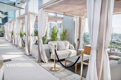 Modern rooftop lounge with white cabanas, pergolas, and cityscape views