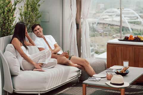 Couple relaxing on a modern daybed on a highrise balcony with city views