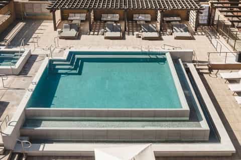 Aerial view of multi-level pool deck with lounge chairs, umbrellas, and modern architectural design