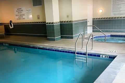 Indoor swimming pool with turquoise water, tiled walls, and metal railings