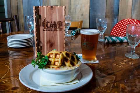 Appetizer plate with waffle-cut potato and beer glass on wooden table at restaurant