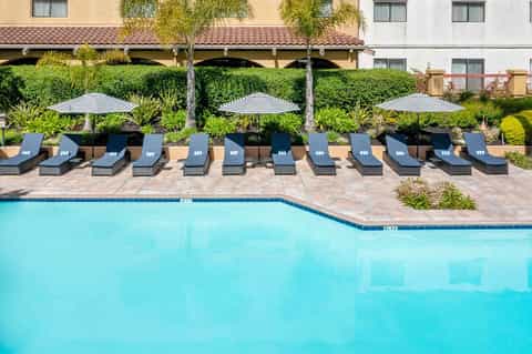 Resort pool with striped umbrellas and lounge chairs beside building