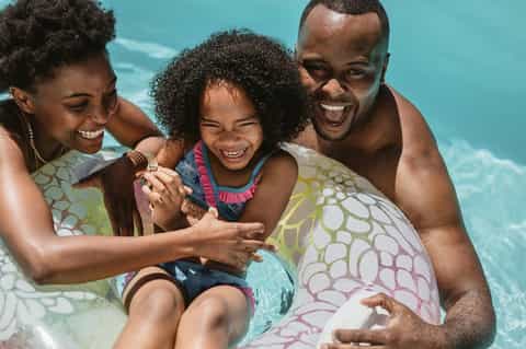 Family enjoying pool time with inflatable float rings and bright turquoise water