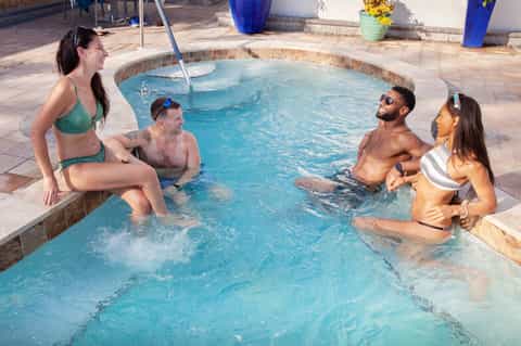 Four guests relaxing in hot tub spa with tropical surroundings