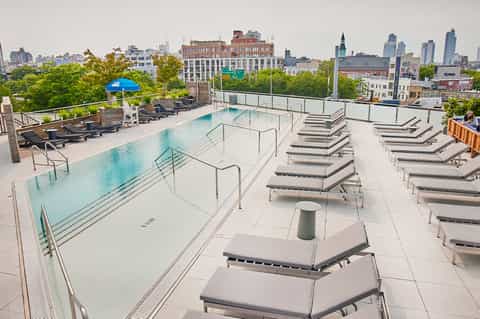 Rooftop pool overlooking urban skyline with lounge chairs and city views